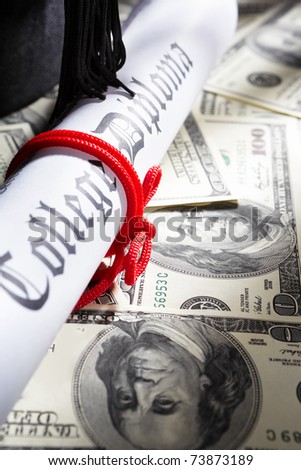 Graduation hat, and diploma certificate on top scattered US dollar bills for expensive education concept
