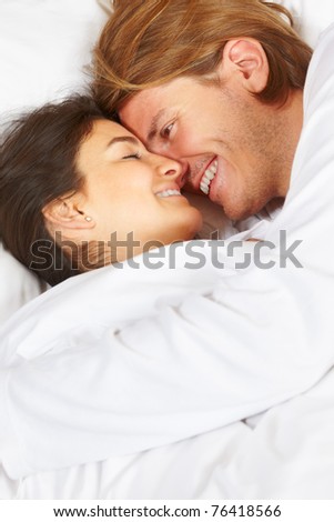 Happy couple showing their romance on fully covered white bed