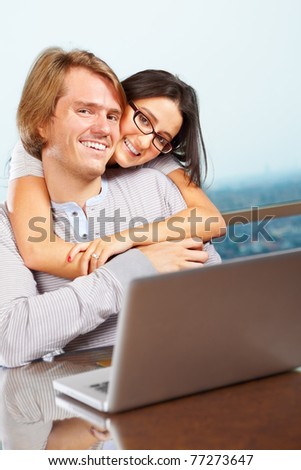 Lady hug her spouse from behind looking very happy in front of the laptop