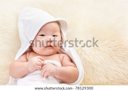 Close up photo shoot of Chinese baby boy covered with white blanket on fur bed