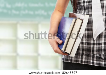 Female student body part holding book in the classroom
