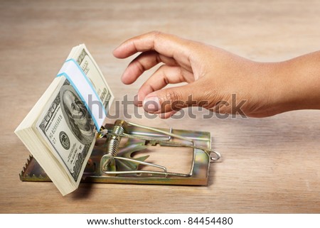 People hand is about to catch the money placed on mousetrap