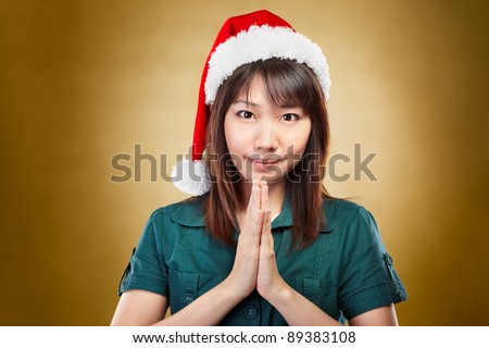 Asian lady with santa hat posing to camera with greeting gesture