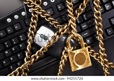 Monitor, keyboard and mouse wrapped by golden chain with locked padlock