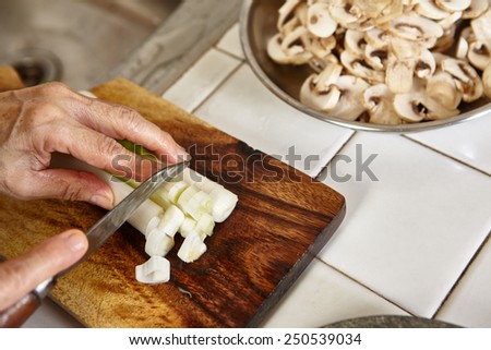Cutting the leek on wooden cutting board, slight movement blur might be noticeable