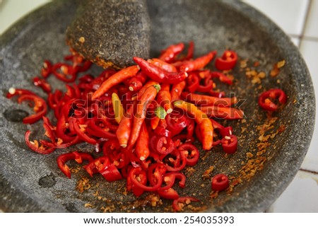 Making sambal, special chili food in Indonesia to eat together with another meal to add hot and spice flavour, all the ingredient crushed using stone pestle on stone mortar