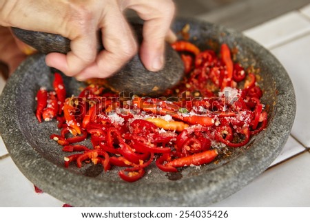 Making sambal, special chili food in Indonesia to eat together with another meal to add hot and spice flavour, all the ingredient crushed using stone pestle on stone mortar
