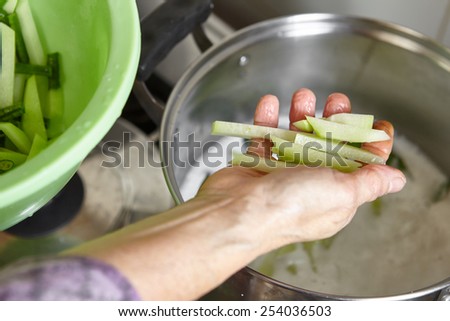 Adding chayote to the cooking pot filled with coconut milk