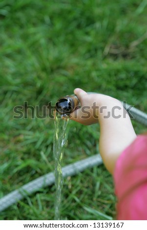 Child holding a running water hose. Water conservation picture