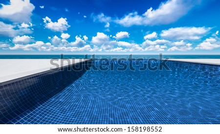 Infinite swimming pool with ocean and clouds in background