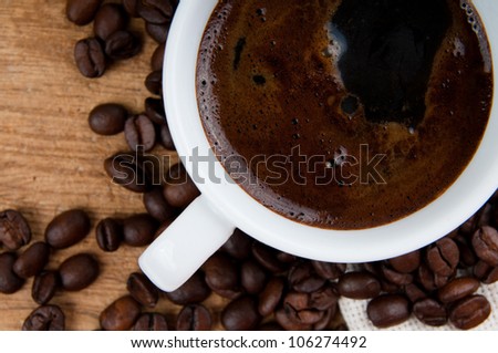 cup of black coffee and coffee beans on a wooden board