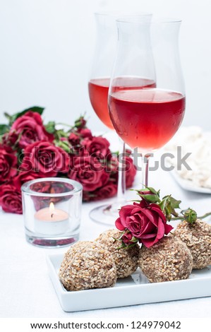 Two glasses of rose wine , fresh flowers, cakes, and snacks on the festive table, home party