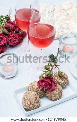Two glasses of rose wine , fresh flowers, cakes, and snacks on the festive table, home party