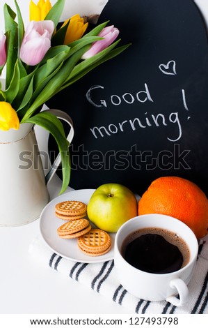 bouquet of tulips in a white jug, morning coffee, fruit and chalk board with the inscription on a white background