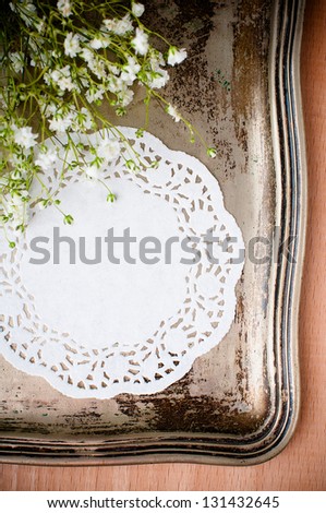 Vintage Nickel Silver tray, delicate white napkin and flowers on a wooden board, close up