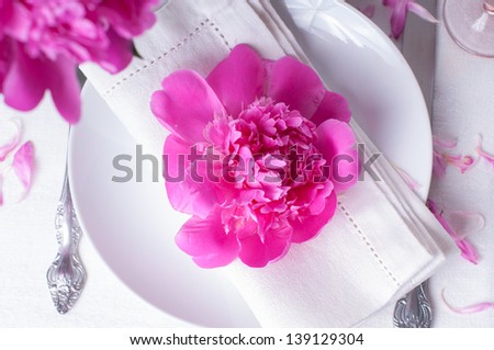 Bright festive table setting with pink peonies, candles and vintage cutlery
