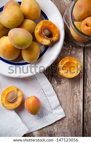 Rustic still life: fresh ripe apricots, antique plates, forks and napkins on wooden table, vintage food