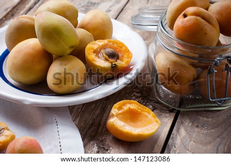 Rustic still life: fresh ripe apricots, antique plates, forks and napkins on wooden table, vintage food