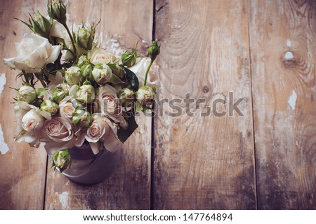 Bouquet of roses in metal pot on the wooden background, vintage style