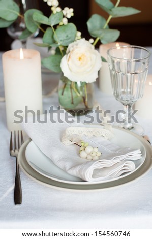 Beautiful festive table setting with flowers, candles, white table cloth and napkins, close-up