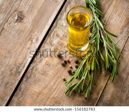 Cooking oil and fresh rosemary on a wooden board, close-up, background is rustic kitchen