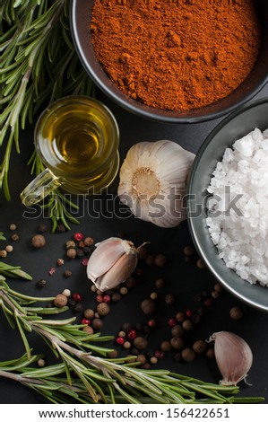 Fragrant spices, rosemary, allspice, garlic, oil and salt on a black background, culinary still life