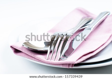 Shiny new cutlery, silverware and a napkin close-up on white background