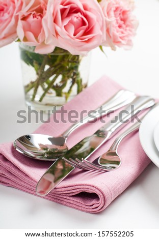 Shiny new cutlery, silverware and a napkin with flowers, close-up on white background