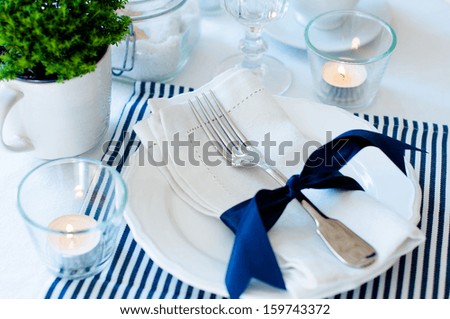 Table setting for breakfast with napkins, cups, plates in navy blue tones on a white background isolated