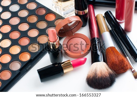 Professional makeup set: eyeshadow palette, lipstick, mascara, blush, powder, make-up brushes and perfume, many cosmetics closeup.