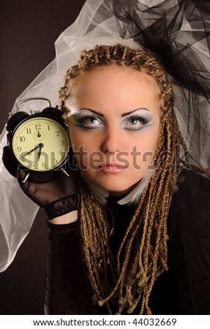 Girl with stage makeup in theatrical costume with clock in her hand