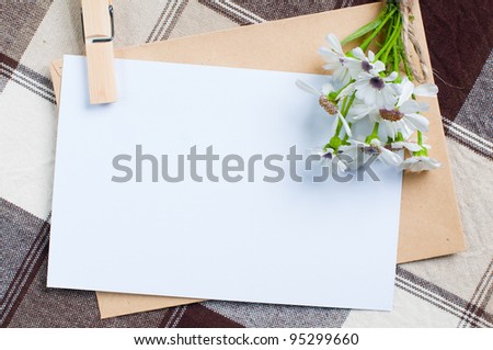 composition of the empty cardboard card with flowers and an envelope on fabric