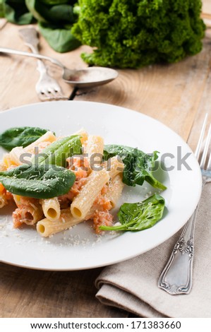 Pasta with salmon and spinach, rigatoni with seafood and parmesan, homemade Italian food on a wooden board