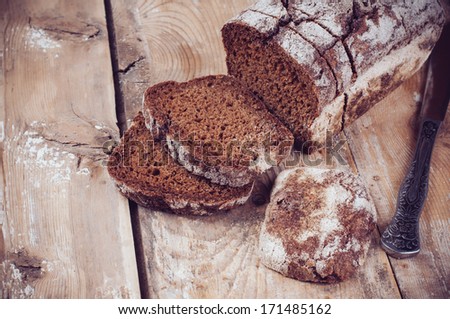 A loaf of fresh rustic wholemeal rye bread, sliced Ã?Â¢??Ã?Â¢??on a wooden board, rural food background.