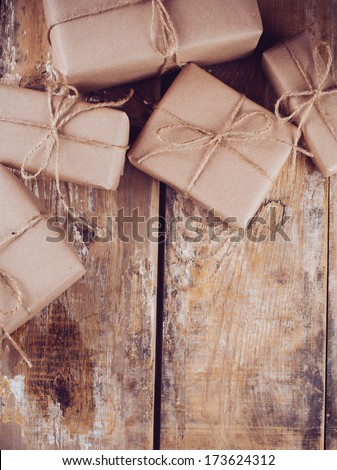 Several gift boxes, postal parcels wrapped in brown kraft paper tied with a rope on a wooden board