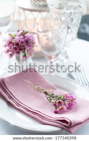 Festive wedding table setting with pink flowers, napkins, vintage cutlery, glasses and candles, bright summer table decor.
