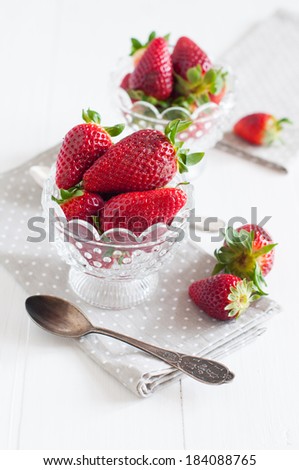 Natural fresh strawberries in a crystal bowl on a wooden board, summer berries, healthy food.