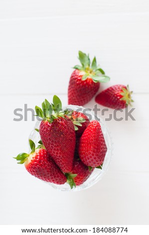 Natural fresh strawberries in a crystal bowl on a wooden board, summer berries, healthy food.