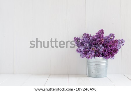 Bouquet of beautiful spring flowers of lilac in a vase on a white vintage wooden board, home decor in a rustic style