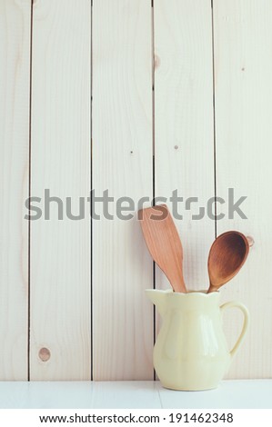 Home Kitchen Decor: vintage cutlery, kitchen utensils in yellow ceramic jug on a wooden board background , cozy arrangement retro style, soft pastel colors.