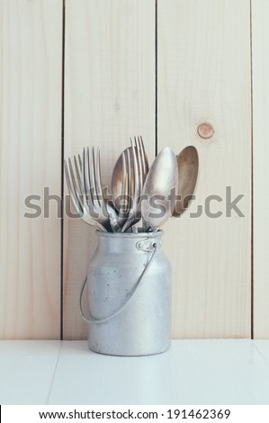 Home Kitchen Decor: vintage cutlery, spoons and forks in zinc can on a wooden board background , cozy arrangement retro style, soft pastel colors.