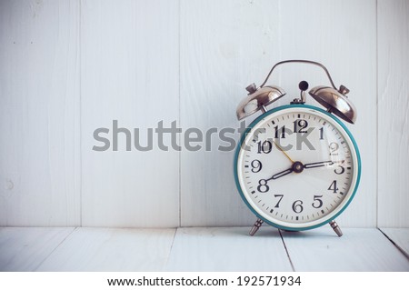 Big old vintage alarm clock with bells, painted white wooden background