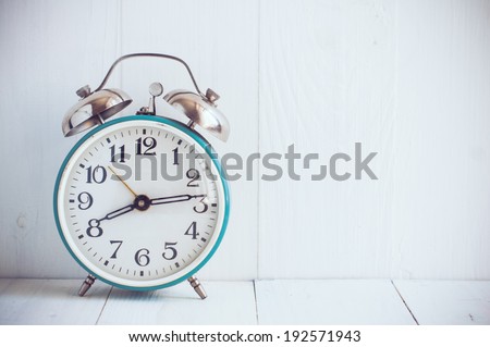 Big old vintage alarm clock with bells, painted white wooden background