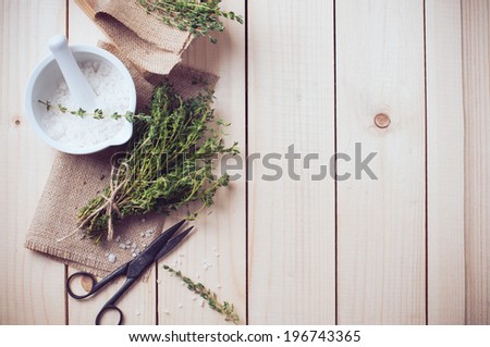 Cozy rustic home kitchen still life, dried herbs thyme, salt in white mortar, old wooden box and vintage scissors on a table background.