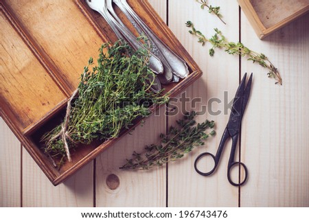 Rustic home kitchen still life, dried herbs, old boxes, antique cutlery and vintage scissors on a wooden table.