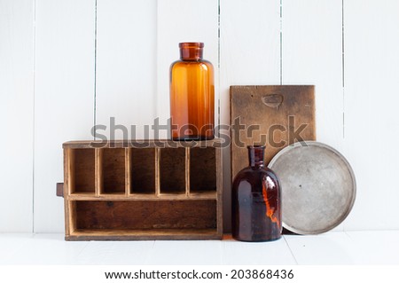 Vintage home decor: old wooden boxes and vintage brown glass bottles on white wooden board, retro home interior.