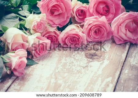 Bouquet of pink roses on old wooden board background, vintage toning