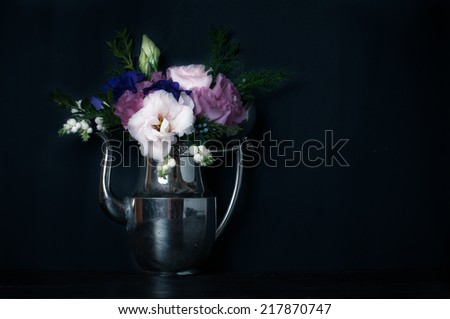 Summer bouquet of purple and pink eustomas in an antique coffee pot on a black background, vintage style, floral decorations