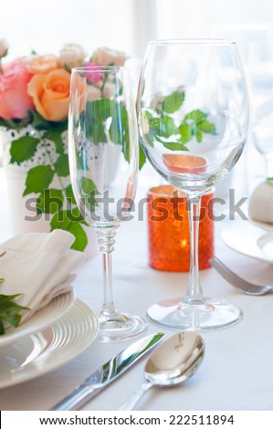 Festive table setting with colorful flowers, cutlery, candles. Wedding table decoration, wineglasses.