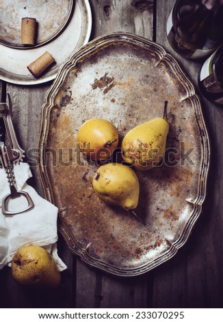 Vintage still life, ripe yellow pears, cupronickel trays, cork and corkscrew on a wooden board